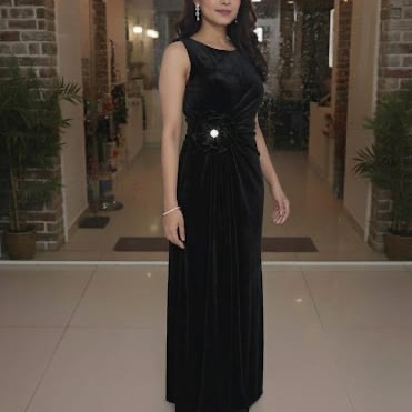 Model in a black one-shoulder draped gown with jeweled waist detail
